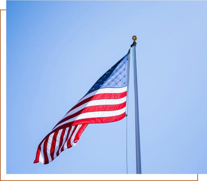 A flag flying in the wind on top of a pole.